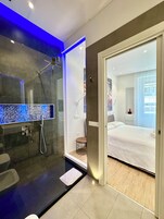Un bagno moderno con doccia vetrata, specchio digitale e WC separato.