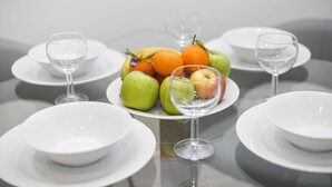A table set with white plates, clear wine glasses, and a fruit arrangement including apples and oranges. - Lux 2 & 3 Bed Apartments in Camden Town FREE WIFI by City Stay Aparts London (London)