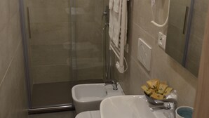 Une salle de bain moderne avec une douche à parois de verre, des toilettes, un lavabo et un porte-serviettes.