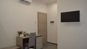 Une chambre d’hôtel moderne équipée d’un bureau, d’une chaise et d’un téléviseur à écran plat fixé au mur.
