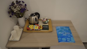 Un plateau de petit-déjeuner avec une bouilloire, des tasses à café et des portions de nourriture, posé sur une table en bois.