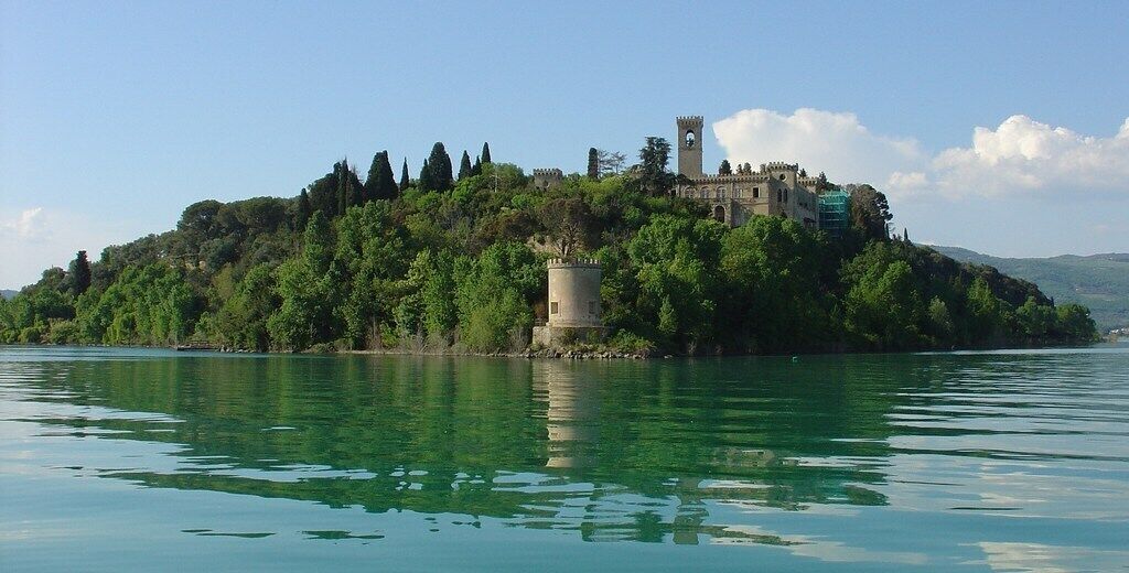 A castle on a lush green island surrounded by calm water.