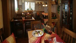 A cozy restaurant interior with wooden furniture, a table set for two with a plate of food and wine glasses. - Hotel Engel (Rheinmunster)