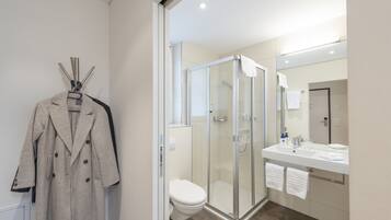 A modern bathroom with a glass-enclosed shower, a white toilet, and a large mirror above the sink.