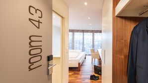 A modern hotel room with a wooden floor, a bed, a desk, and a chair. - Hotel Rössli (Zuzwil)