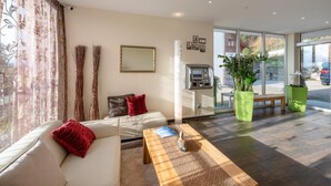 A modern hotel lobby with a sofa, a coffee table, and large windows. - Hotel Rössli (Zuzwil)