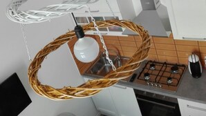 A kitchen with a modern design, featuring a gas stove, a microwave, and a hanging light fixture made of woven material. - Déjà Vu (Crotone)