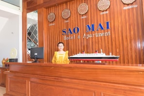 Una reception del Sao Mai Hotel & Apartment con orologi che mostrano l'ora di diverse città e un modellino di nave.