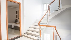 A modern hotel room with a large mirror, a bed, and a staircase with glass railings.