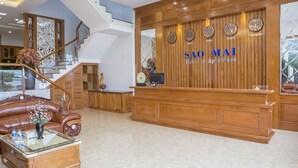 A reception area with a wooden reception desk, a sofa, and a staircase.