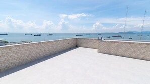 A rooftop terrace with a view of the sea and ships.