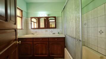 A bathroom with a wooden vanity, two sinks, a mirror, and a bathtub.