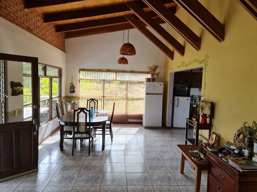 A kitchen with a dining area, a refrigerator, and a window with a view of greenery.