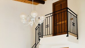 Un intérieur à deux niveaux, avec un escalier, un lustre et une porte en bois.
