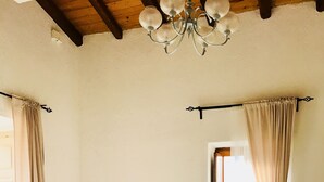 Un coin repas comprenant une table ronde, quatre chaises, un lustre, un buffet blanc et une fenêtre avec des rideaux.