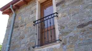 Un bâtiment en pierre avec une porte en bois et une fenêtre ornée d’une grille en métal.