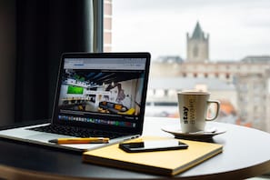 Una computadora portátil sobre una mesa con una taza de café, un teléfono inteligente y una libreta.