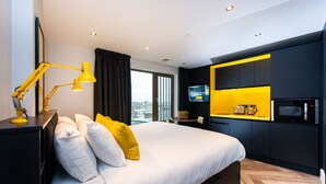Een moderne hotelkamer met een groot bed, een bureau met lamp, een flatscreen-tv en een magnetron.