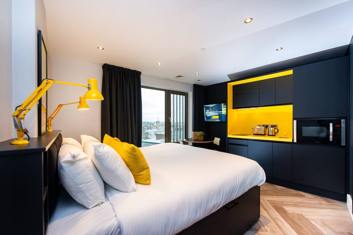 Een moderne hotelkamer met een groot bed, een bureau met lamp, een flatscreen-tv en een magnetron.