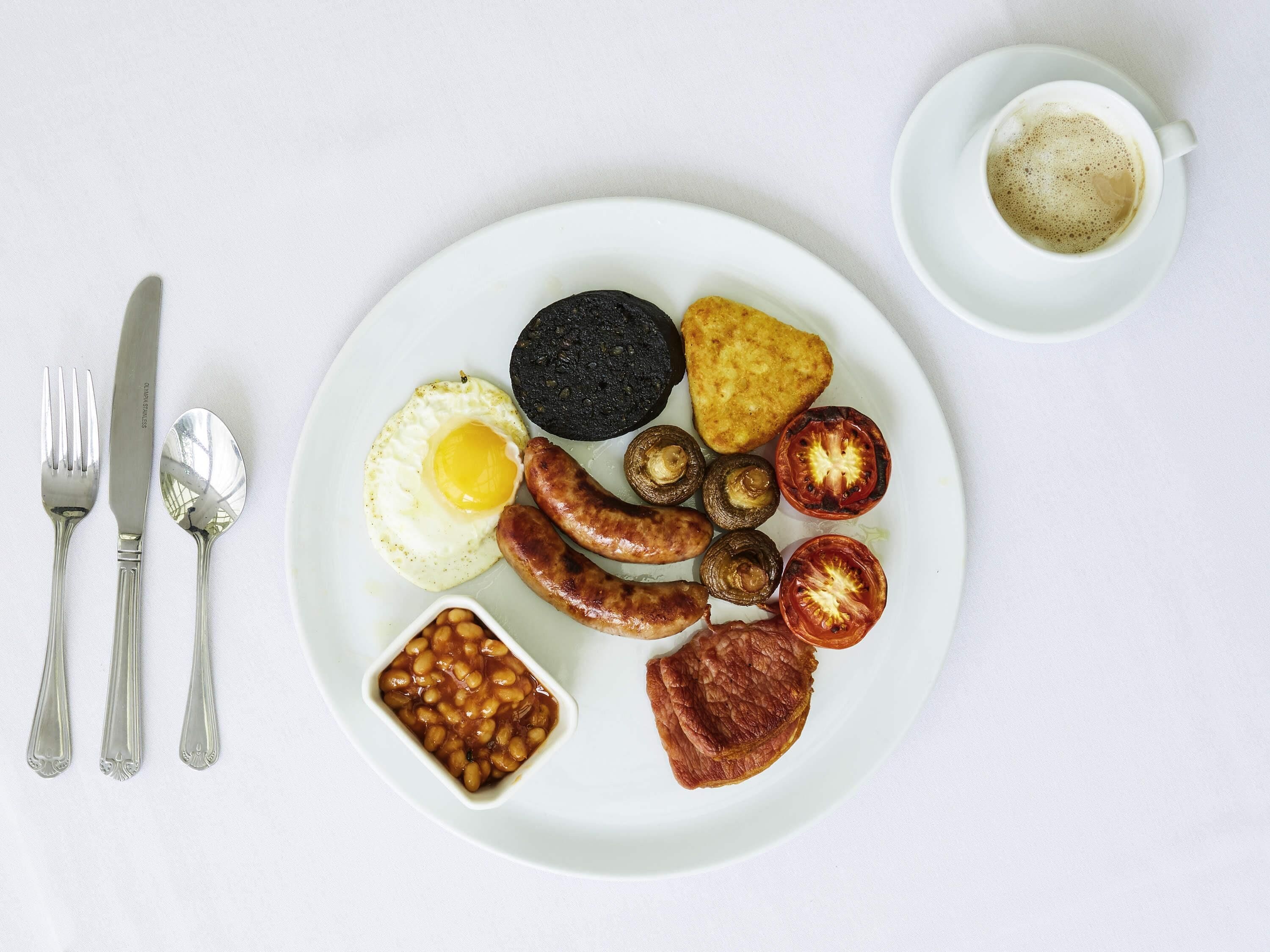 Un plato de comida para el desayuno con huevos, salchichas, champiñones y tomates.