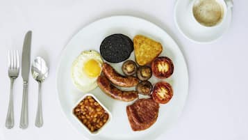 Un plato de comida para el desayuno con huevos, salchichas, champiñones y tomates.