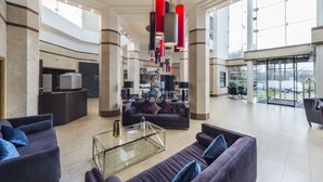 A spacious lobby with a high ceiling, modern furniture, and a large glass door leading outside. - Mercure St Helens (St Helens)