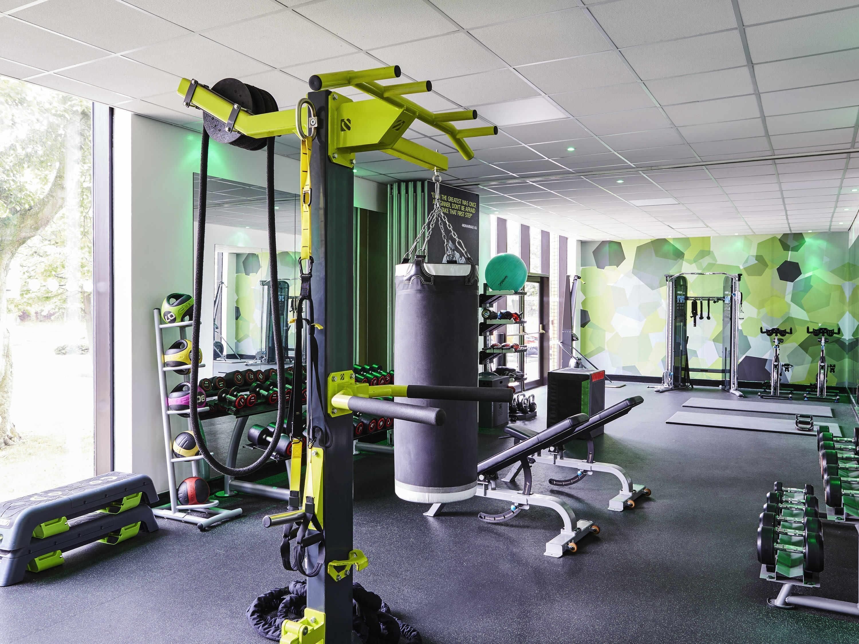 Un gimnasio con diversos equipos de ejercicio, entre ellos máquinas de pesas y pesas libres.