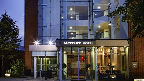 A Mercure Hotel with a modern glass facade, a visible entrance, and a sign indicating 84 bedrooms and conference facilities. - Mercure St Helens (St Helens)