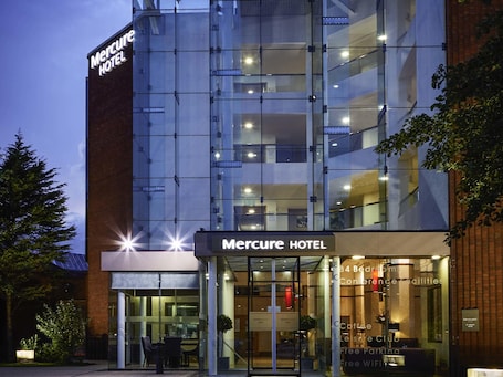 A Mercure Hotel with a modern glass facade, a visible entrance, and a sign indicating 84 bedrooms and conference facilities.. Mercure St Helens