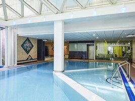 An indoor swimming pool with clear water, tiled walls, and a visible leisure club named 'PYRAMID' in the background.