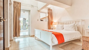 Un dormitorio con una cama, una mesita de noche, una silla, una ventana y una puerta.