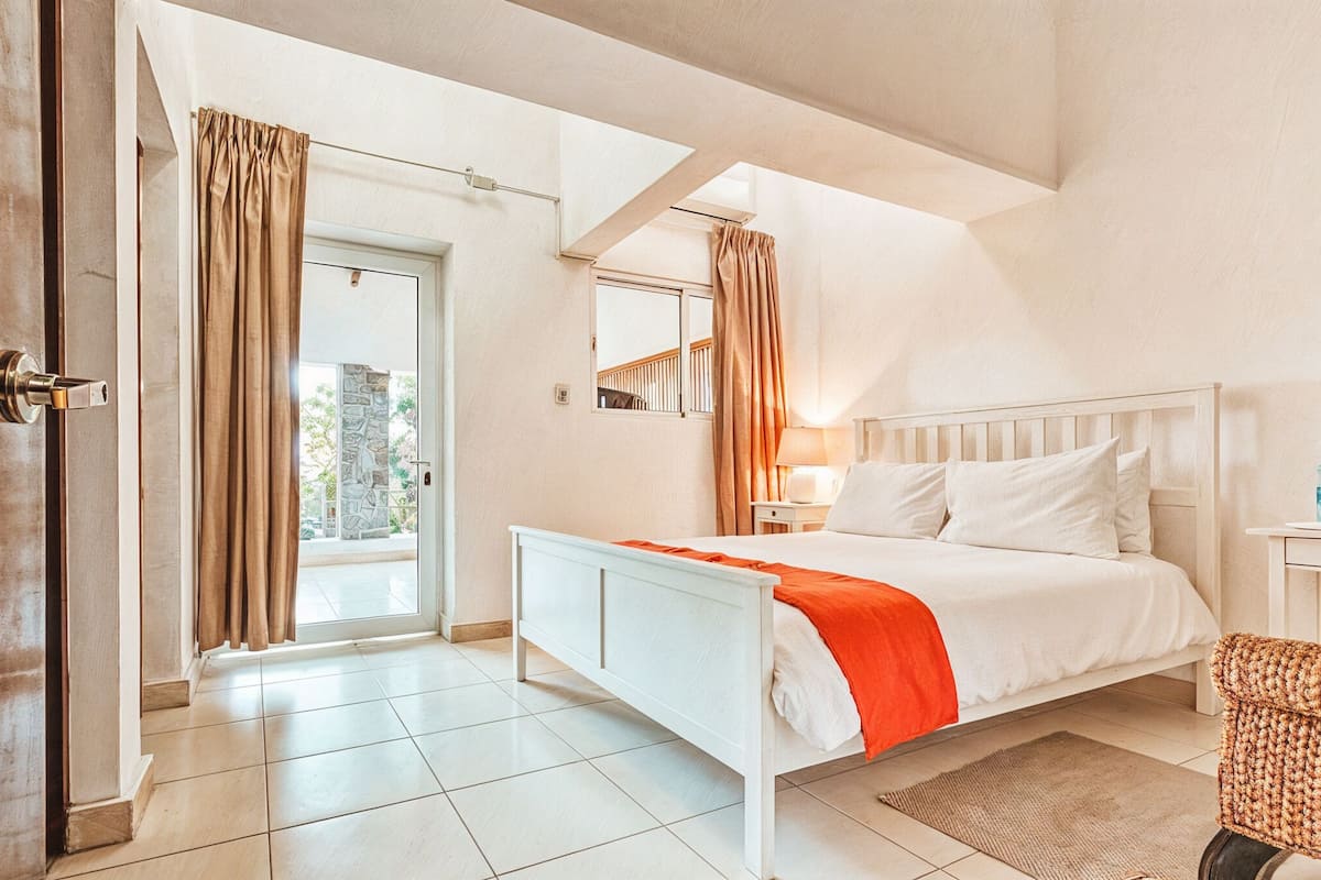 Ein Schlafzimmer mit einem Bett, einem Nachttisch, einem Stuhl, einem Fenster und einer Tür.