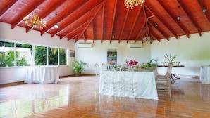Amplia habitación con techo alto, vigas de madera, candelabro y una mesa dispuesta para cenar.