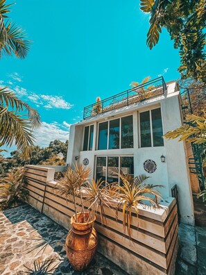 A modern building with large windows, a balcony, and a stone pathway. - Ekolojik Resort (Cap-Haitien)