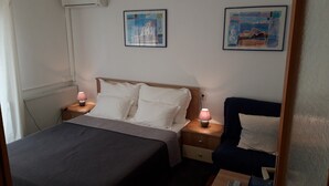 A neatly arranged bedroom with a bed, bedside tables, and two wall-mounted paintings.