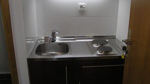 A compact kitchen with a sink, a stove, and black cabinets.