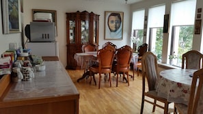 A dining area with wooden chairs and a table, a cabinet with glass doors, and a painting on the wall. - Laugar Guesthouse (Laugar)