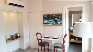 A small, modern room with a white desk, two wooden chairs, a painting of a street scene, and a lamp. - B&B Unique (Sorrento)