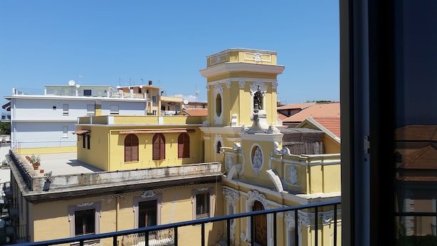 A yellow building with ornate architectural details and a bell tower, surrounded by other buildings. - Younique (Sorrento)
