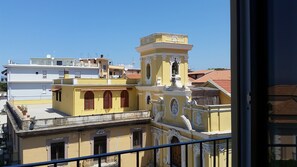 A yellow building with ornate architectural details and a bell tower, surrounded by other buildings. - Younique (Sorrento)