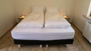 A double bed with white linens and two bedside tables with lamps. - Guesthouse Hvitafell (Laugar)