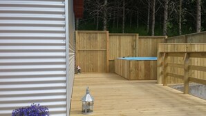 A wooden deck with a metal railing, a small blue pool, and a metal lantern. - Guesthouse Hvitafell (Laugar)