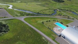 An aerial view of a golf course with a swimming pool and a large building. - Guesthouse Hvitafell (Laugar)