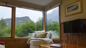 Una habitación acogedora con un ventanal grande, una cama, un televisor y una mesa de madera.