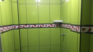 Un bany petit amb rajoles verdes, un vàter, un bidet i una zona de dutxa.