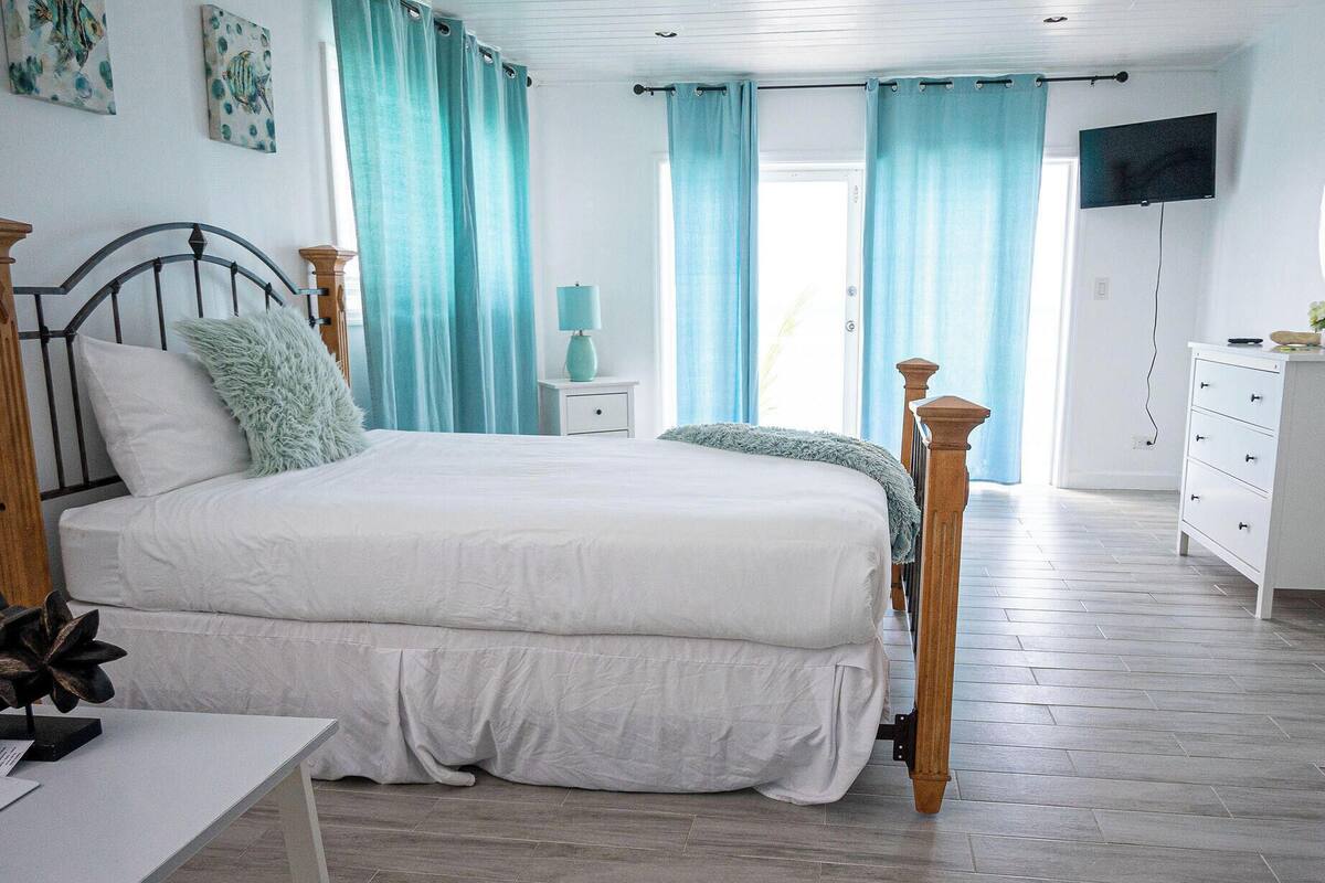 A bedroom with a bed, a nightstand, a dresser, and a television.