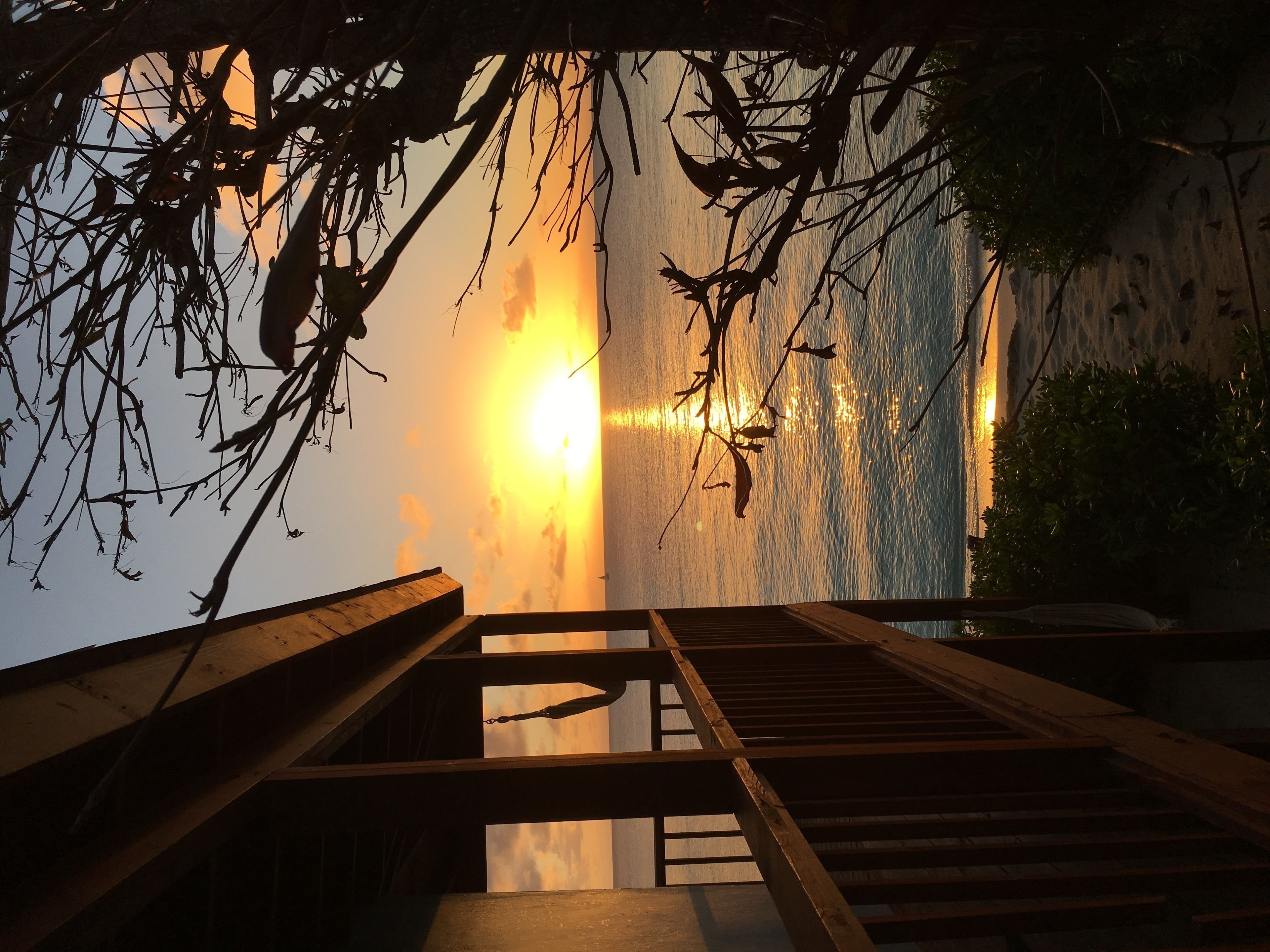 Un escalier en bois mène à un balcon d’où l’on peut admirer un coucher de soleil sur l’eau.