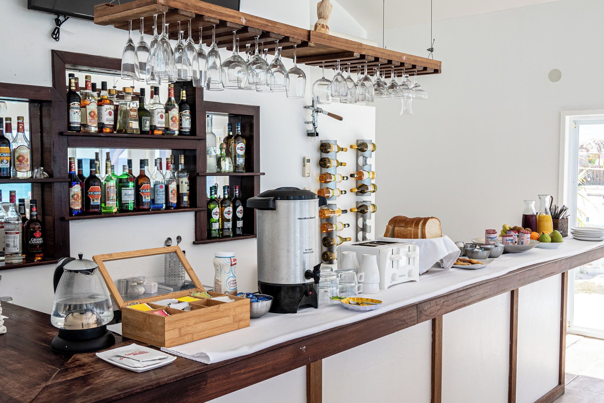 A bar area with shelves of liquor bottles, a coffee machine, and a variety of glasses and utensils.