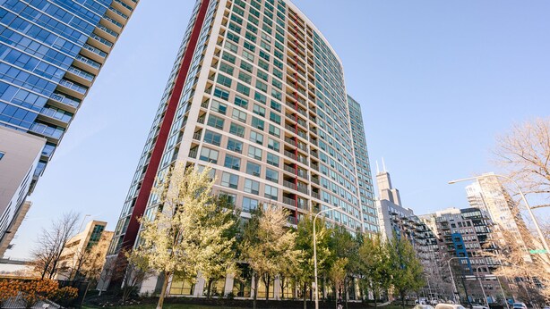 Een hoog gebouw met een modern architectonisch ontwerp, gekenmerkt door een opvallende rode verticale streep en meerdere balkons.