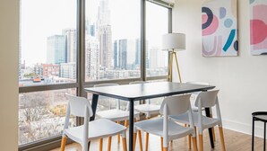 Een moderne kantoorruimte met een groot raam met uitzicht op de stad, een ronde tafel met stoelen en abstracte kunst aan de muur.